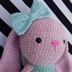 A close-up of the plush bunny's sweet face. The soft texture of the yarn makes this toy incredibly huggable and safe for little ones.