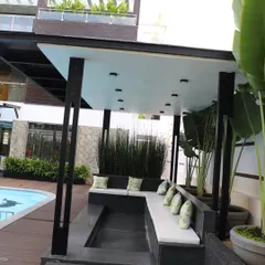 Another view of the sunken poolside lounge, showing the comfortable cushioned seating and the backdrop of tall Traveler's Palms (Strelitzia nicolai) that provide a sense of enclosure and a tropical feel.