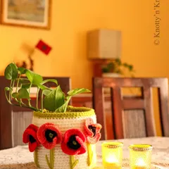 My Remembrance Poppy Basket, featuring bright red 3D crochet poppies on a cream-coloured base. It adds a lovely pop of colour as a planter cover on a dining table.