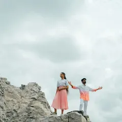 An adventurous pose on a rocky cliff against a cloudy sky. This dramatic shot captures a sense of freedom and shared adventure.