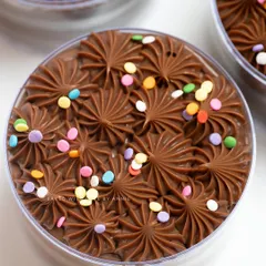 A close-up of my Belgian Milk Chocolate Cake Tub. Topped with piped ganache and colorful confetti, this nostalgic and delicious treat is perfect for the festive season and easy to serve.