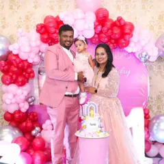 Family celebrations call for coordinated style. This family looks picture-perfect in matching shades of pink for a first birthday party, with a smart suit for him and an elegant gown for her.