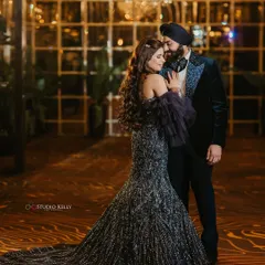 A glamorous portrait of the couple at their reception, the bride's glittering gown trailing behind her, creating a stunning silhouette.