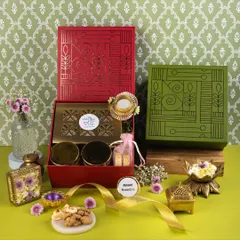 A colorful composition of red and green festive boxes, styled with fresh flowers and brass elements to highlight the brand's unique packaging.