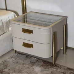 The Solitaire bedside table is a testament to both design and functionality. It features a beautiful glass top revealing a partitioned storage compartment, sleek metal legs, and drawer pulls that match the bed's metal accents.