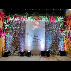 A chic and modern sangeet or reception stage featuring a dazzling silver shimmer wall. A custom 'Better Together' neon sign and the couple's names, Sejal and Manish, add a personal touch, perfect for a glamorous party photo booth.