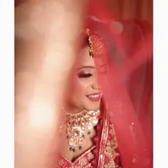 A soft and dreamy close-up of the bride smiling, with her red veil creating a beautiful, artistic blur in the foreground.