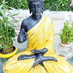 This unique Buddha statue features a black body with a contrasting yellow robe. It's a modern take on a classic symbol of peace.