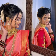 A moment of reflection for the bride. This profile showcases the intricate hair bun, glowing skin, and the beautiful drape of her pink and red `Paithani` saree.