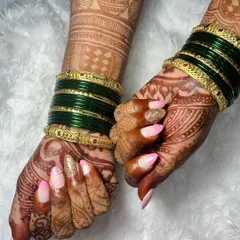 A beautiful temporary extension set for a bride, featuring a soft pink and white ombré effect. The look is elevated with a full gold glitter accent nail, perfectly complementing her green bangles and detailed mehndi design.