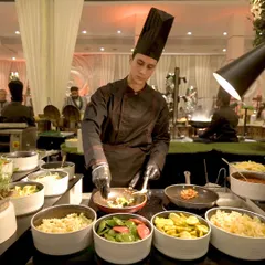 A chef at our live pasta station, stir-frying fresh ingredients. Guests can choose their own vegetables, sauces, and pasta, creating a personalized dish made right before their eyes.