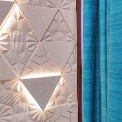 A feature wall with intricate marble engravings becomes a piece of art through the play of light. We use backlighting to highlight the 3D patterns, adding depth and a unique focal point to the living space.