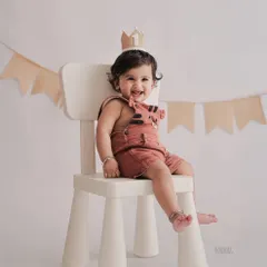 Dressed in cute overalls and a birthday crown, this little one is ready for his first birthday photoshoot. We use simple props like this modern chair to keep the focus on your child.