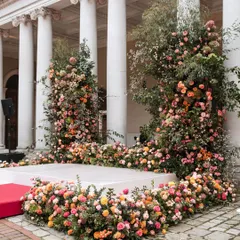 A lush, organic floral mandap set against the classical columns of a historic English palace. We love the contrast of vibrant, wild-feeling flowers with formal architecture.
