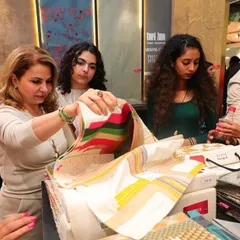 A client explores a vibrant, striped fabric sample at our booth during the Ajio Luxe Weekend. This moment captures the excitement of the design process, where clients can see and feel the quality of our collections firsthand.