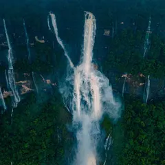 The majestic Nohkalikai Falls in Meghalaya, India's tallest plunge waterfall, seen from the air. The mist and spray create an ethereal, dreamlike atmosphere.