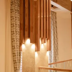 A closer look at the custom-designed wooden lighting feature over a staircase. The warm spotlights create a beautiful play of light and shadow, enhancing the architectural details of the space.