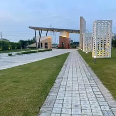 The entrance to the Kanpur housing community at dusk. The design incorporates illuminated decorative screens and a cantilevered roof, creating a welcoming and secure entry point that is both functional and architecturally significant.