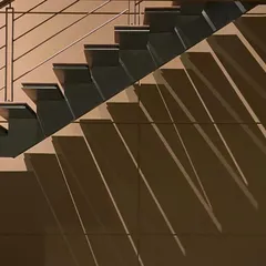 A minimalist and modern staircase design, where the sharp lines of the steps and railing create a dynamic play of diagonal shadows. This image highlights our focus on intentional design, where even simple elements are elevated through light and form.
