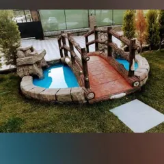 I build charming hardscape elements like this decorative wooden-style bridge over a small, custom-built pond. It's a perfect feature to add a touch of whimsy and focus to a garden.