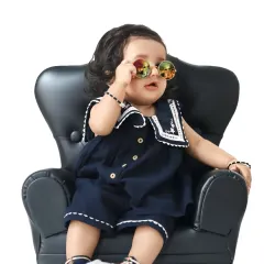 This little one has serious style, posing in a miniature armchair and adjusting a pair of cool, round sunglasses.