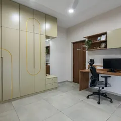 A spacious home office with a long wooden desk and an ergonomic chair. The room includes floor-to-ceiling wardrobes with unique gold inlay details, providing extensive storage while maintaining a clean, sophisticated look.