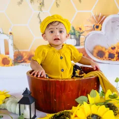This little baby in a yellow dress looks curious and cute in our sunflower-themed set. We capture these candid expressions that make each photo special.