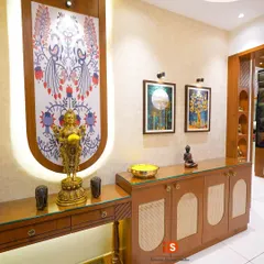 A closer look at the traditional foyer console, highlighting the custom backlit panel with Indian folk art, the elegant brass statue, and the cane-fronted cabinets.