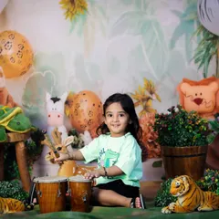 This two-year-old is making some noise in our jungle theme, playing on a set of bongo drums surrounded by her favorite animal friends.