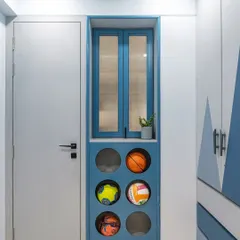 Smart storage is key in any kid's room. This custom-built unit in a calming blue finish features designated circular compartments for sports balls, keeping them organized and easily accessible while adding a playful, graphic element to the room's entryway.