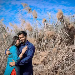 Finding a quiet moment together amidst nature. This outdoor pre-wedding photo captures an intimate embrace against a backdrop of clear blue skies and wild pampas grass, highlighting the couple's connection.