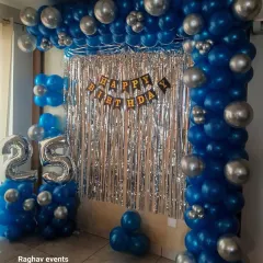 A stylish wall decoration for a 25th birthday. This setup features a blue and silver balloon frame around a silver shimmer curtain, with 'Happy Birthday' and number '25' foil balloons.