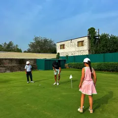A family enjoys a putting lesson on the green. It's a great way to introduce kids to the sport in a relaxed and playful setting.