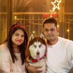 A picture perfect holiday photo with Walt the husky and his loving parents, all decked out in festive gear and surrounded by twinkling lights.