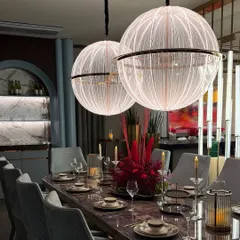 A luxurious dining room setup featuring a dramatic floral centerpiece and stunning globe pendant lights. We work to enhance the existing beauty of a space.