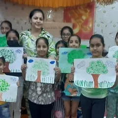 Proudly presenting their masterpieces. Our art sessions conclude with children showing off their work, like these beautiful tree paintings, which helps build their confidence and sense of achievement.
