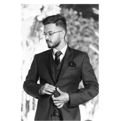 A dapper black and white portrait of the groom. Adjusting his suit, he looks sharp and confident, a classic shot that captures his style on the big day.