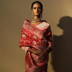 A rich, red Banarasi saree styled with a traditional nath and choker. This look is a celebration of heritage weaves and classic bridal beauty, perfect for a bride's main ceremony or reception.