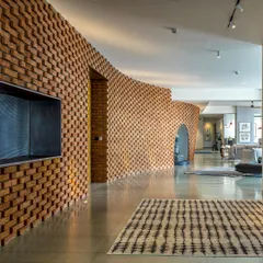 In the Sampurna Residence, we used a curving brick wall to create an 'animated streetscape' within the home. This element guides movement and defines space, transforming a simple corridor into an artistic and experiential journey.