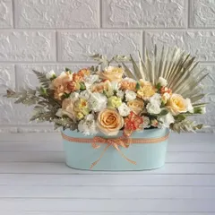 A stunning luxe arrangement of peach and white carnations and roses in a modern blue box. This no-fuss, all-wow arrangement is perfect for elevating any space or celebration.