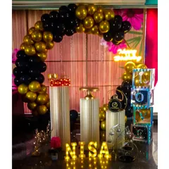 For a bold and dramatic look, we designed this black and gold metallic balloon arch. The setup is completed with matching pedestals, marquee letters for the name, and other decorative props to create a cohesive, high-impact party theme.