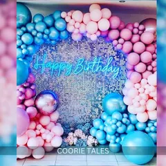 Light up your birthday with this dazzling setup. A shimmering silver sequin wall provides the perfect backdrop for a "Happy Birthday" neon sign, framed by a vibrant pink and blue balloon arch for a fun, party-ready look.