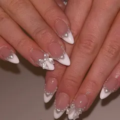 A modern take on bridal nails, these feature a classic French tip base on stiletto extensions. We added 3D pearl hearts and delicate silver bows to create a look that is both romantic and incredibly chic.