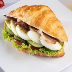 Our Bacon and Egg Croissant Sandwich. A flaky, buttery croissant filled with crispy bacon, sliced boiled eggs, fresh lettuce, and tomato for a hearty and delicious breakfast or lunch.