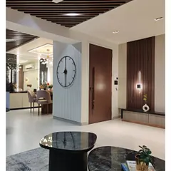 An entryway sets the tone for the entire home. Here, I used vertical wood fluting and a statement wall clock to create a warm welcome, leading into a living space defined by its clean lines and sophisticated ceiling rafters.