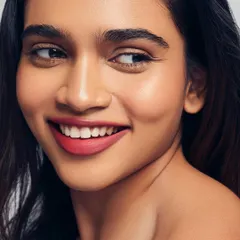 Radiant skin and a happy smile. This portrait showcases a healthy, glowing complexion paired with a beautiful red-pink lip. It's a perfect example of fresh and modern beauty.