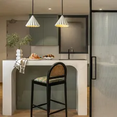 We transformed a once-dimly lit kitchen into a bright, functional heart of the home. Muted sage green cabinetry brings freshness, while the custom-curved island serves as a central gathering spot, seamlessly connecting to the dining area through pocket doors with fabric-sandwiched glass.