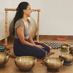 A portrait of one of our graduates, now a confident sound meditation facilitator. Our training empowers students to start their own practice, surrounded by the instruments of healing like Tibetan bowls and gongs.