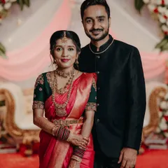 The happy couple posing for a photo. The bride is wearing our custom green blouse with her red Muhurtham saree.