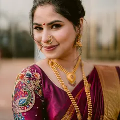 A close-up portrait of the bride, Shruti, showcasing the exquisite peacock embroidery on her blouse and her traditional Maharashtrian jewelry.